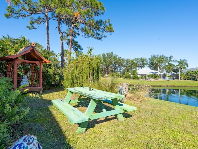 view of property's community with a lawn and a water view