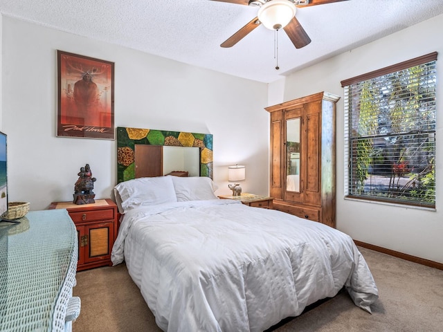 carpeted bedroom featuring ceiling fan and a textured ceiling