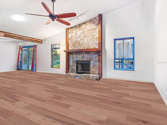 3888 Shady Brook Ln, Sarasota, FL 34243 - unfurnished living room featuring ceiling fan, a textured ceiling, light wood-style flooring, rail lighting, and a stone fireplace