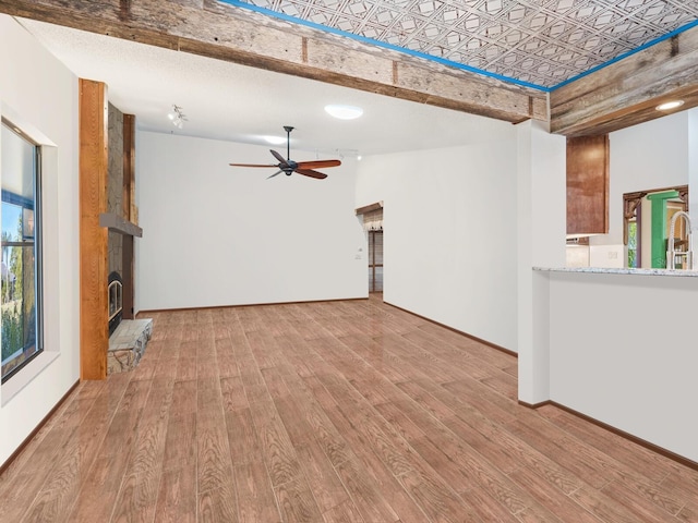 3888 Shady Brook Ln, Sarasota, FL 34243 - unfurnished living room featuring wood finished floors, a ceiling fan, a fireplace with raised hearth, a sink, and baseboards