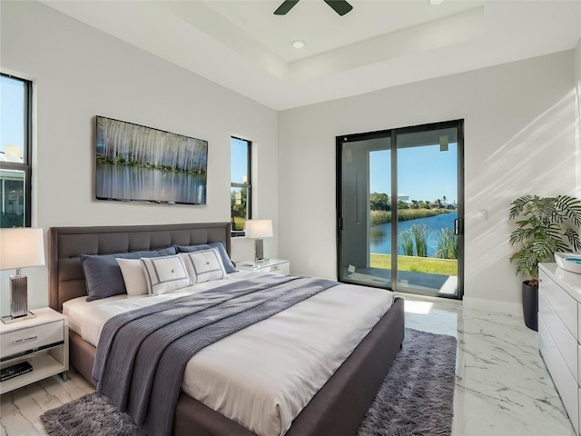 bedroom featuring ceiling fan, access to exterior, a water view, and a tray ceiling