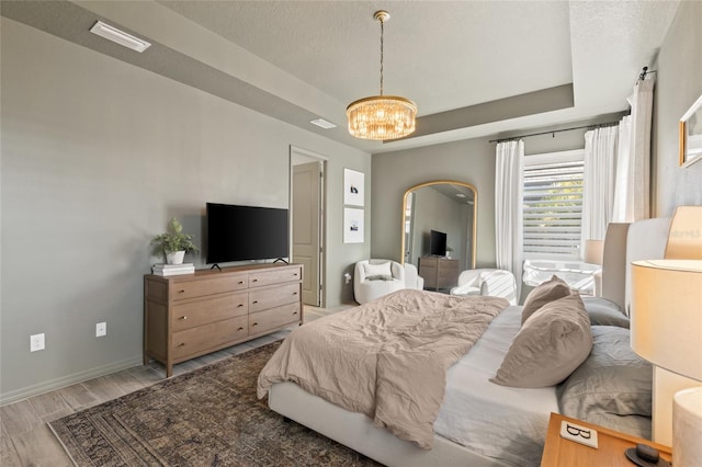 bedroom featuring a notable chandelier, a textured ceiling, and light hardwood / wood-style flooring