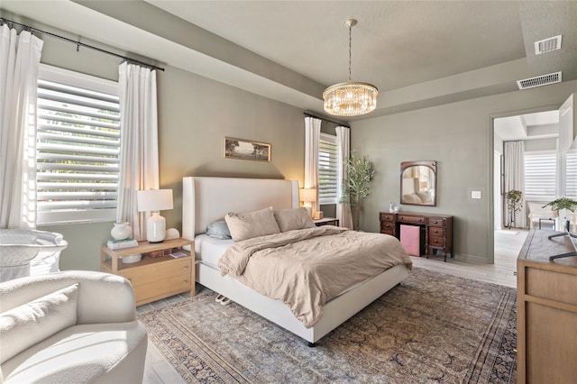 bedroom with hardwood / wood-style floors and an inviting chandelier