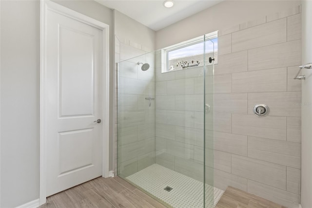 bathroom featuring a tile shower and wood-type flooring