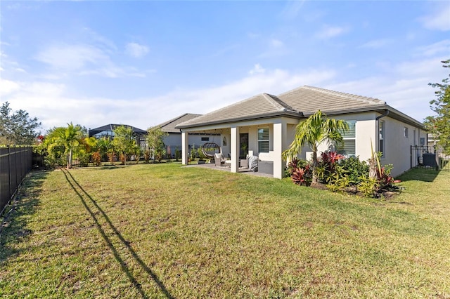 rear view of house with a patio area, a yard, and central AC