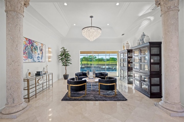 living room featuring a tray ceiling, ornate columns, a chandelier, and ornamental molding