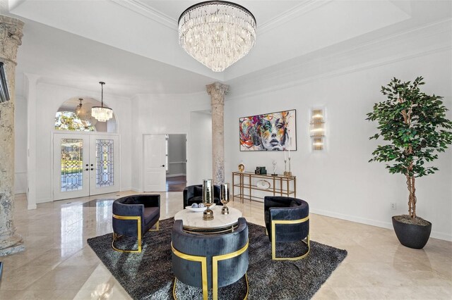 living room with french doors, ornate columns, a notable chandelier, and crown molding