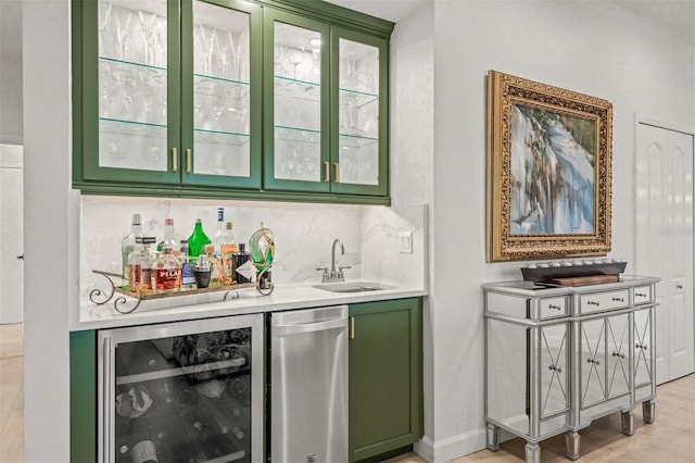 bar featuring sink, beverage cooler, green cabinetry, decorative backsplash, and light wood-type flooring