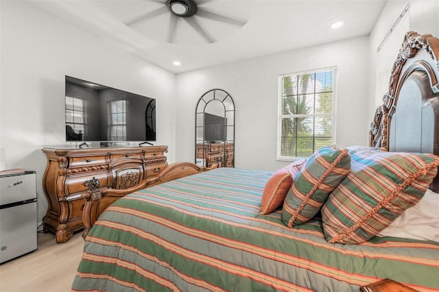 bedroom featuring light hardwood / wood-style floors, stainless steel refrigerator, and ceiling fan