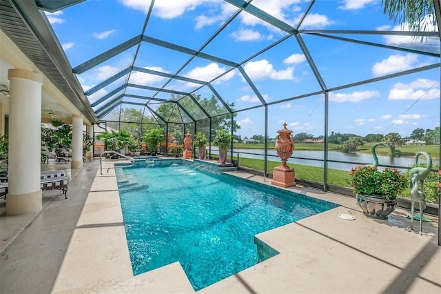 view of pool featuring glass enclosure, ceiling fan, pool water feature, a patio area, and a water view