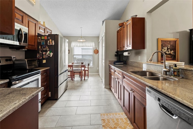 kitchen featuring lofted ceiling, sink, light tile patterned floors, appliances with stainless steel finishes, and decorative light fixtures