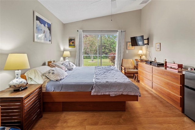 bedroom with ceiling fan, stainless steel refrigerator, and vaulted ceiling