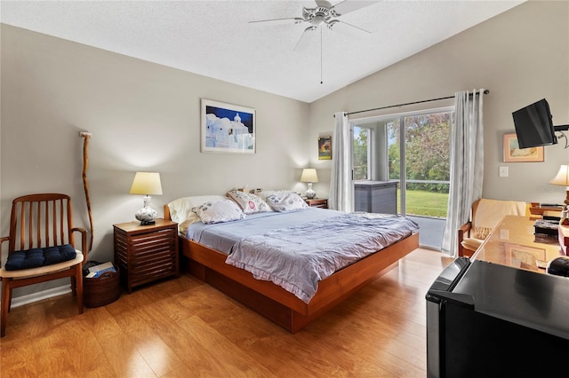 bedroom with access to exterior, a textured ceiling, vaulted ceiling, ceiling fan, and light hardwood / wood-style floors