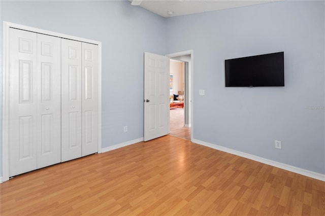 unfurnished bedroom with a closet, light hardwood / wood-style flooring, and a towering ceiling