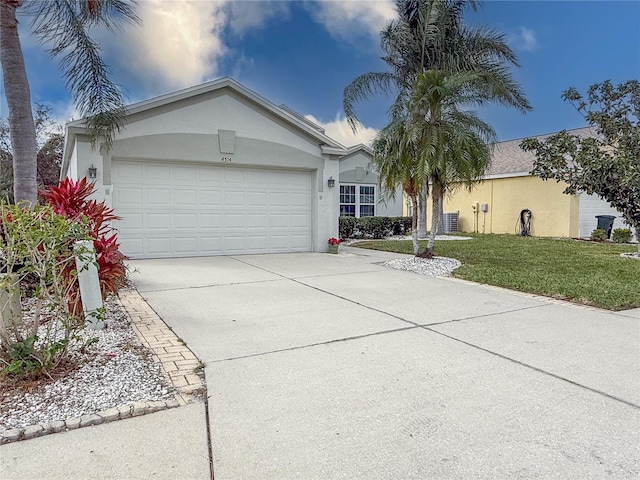 single story home with a front lawn, central AC unit, and a garage