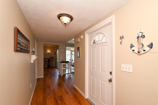 foyer entrance with dark hardwood / wood-style flooring and a textured ceiling