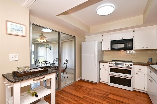 kitchen with range, white cabinetry, hardwood / wood-style floors, and white refrigerator