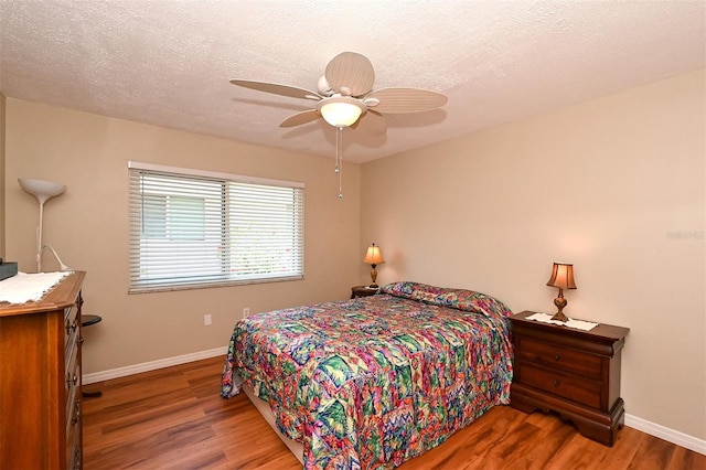 bedroom with hardwood / wood-style floors, ceiling fan, and a textured ceiling