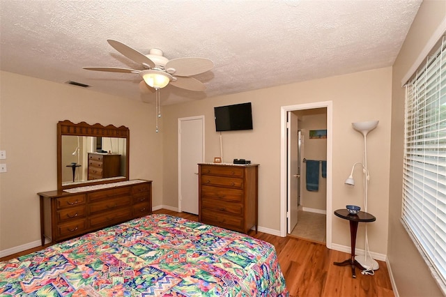 bedroom with multiple windows, ceiling fan, ensuite bath, and light wood-type flooring