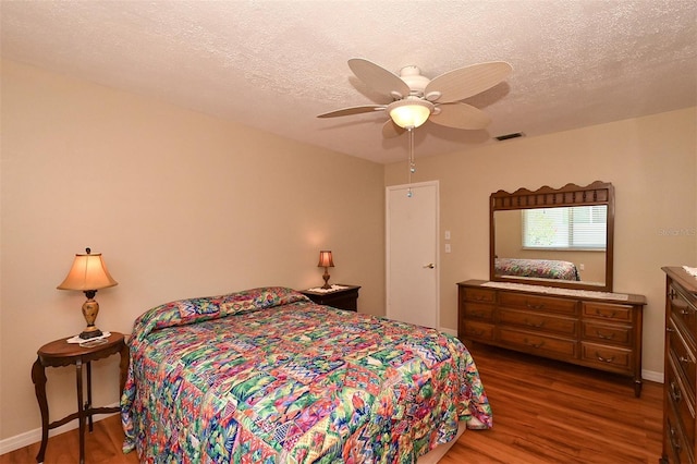 bedroom featuring wood-type flooring, a textured ceiling, and ceiling fan