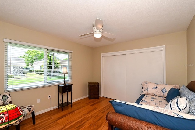 bedroom featuring ceiling fan, a closet, dark wood-type flooring, and a textured ceiling