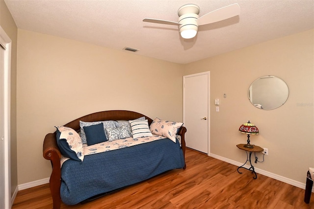 bedroom featuring wood-type flooring, a textured ceiling, and ceiling fan