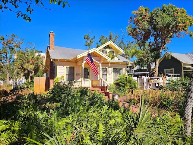 bungalow-style house featuring a chimney and fence