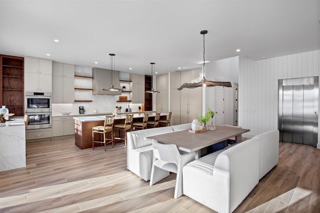 dining area featuring elevator and light hardwood / wood-style floors