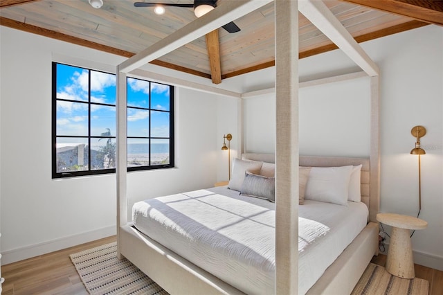 bedroom featuring ceiling fan, wooden ceiling, beamed ceiling, a mountain view, and light wood-type flooring