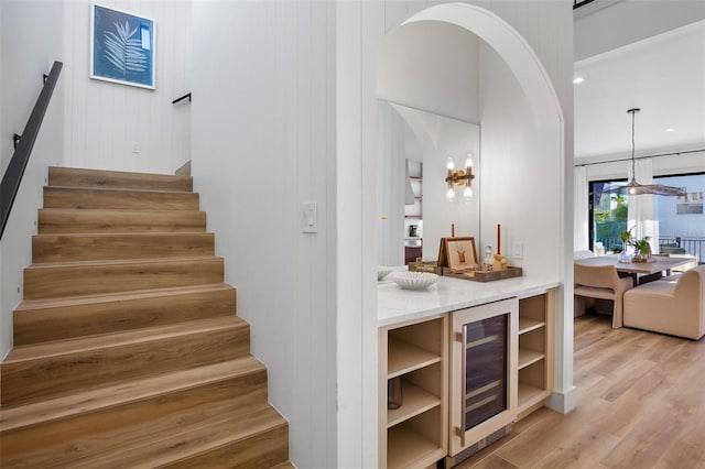 stairway featuring wine cooler, wood walls, and hardwood / wood-style floors