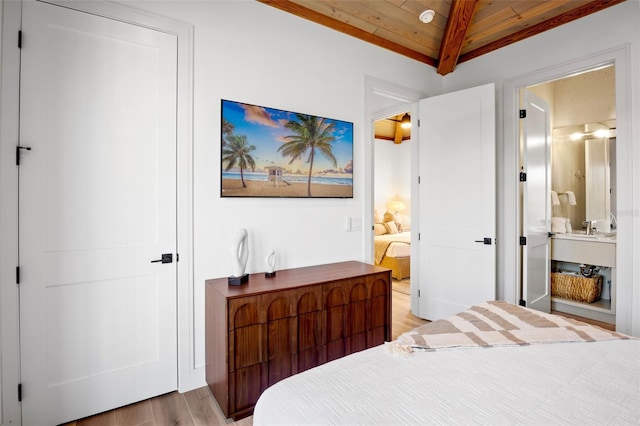 bedroom with vaulted ceiling with beams, ensuite bath, wooden ceiling, and wood-type flooring