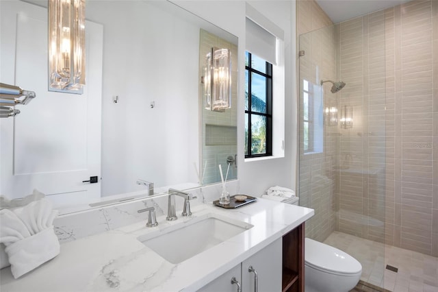 bathroom with a tile shower, vanity, and toilet