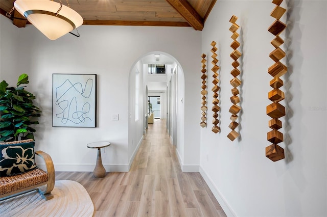 hallway featuring lofted ceiling with beams, light hardwood / wood-style floors, and wood ceiling