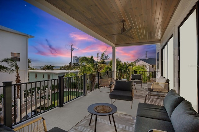 patio terrace at dusk featuring a balcony and an outdoor living space with a fire pit