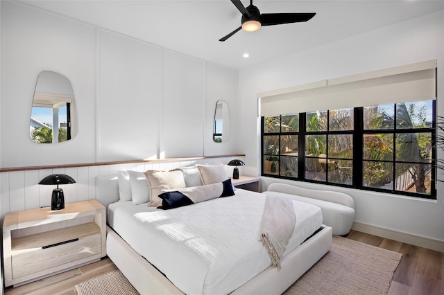 bedroom featuring hardwood / wood-style flooring, ceiling fan, and multiple windows