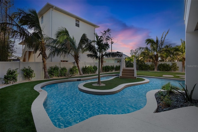 pool at dusk featuring a yard