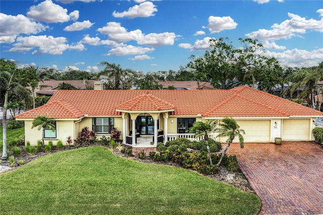 mediterranean / spanish home with a porch, a garage, and a front lawn