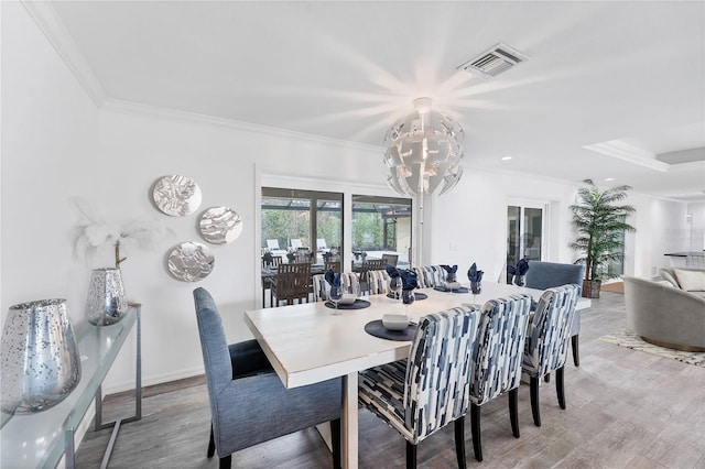 dining area with a chandelier, light hardwood / wood-style floors, and ornamental molding