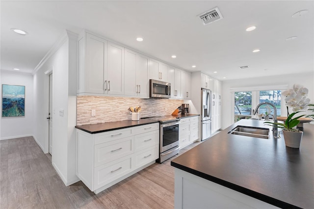 kitchen with white cabinets, crown molding, sink, light hardwood / wood-style flooring, and appliances with stainless steel finishes