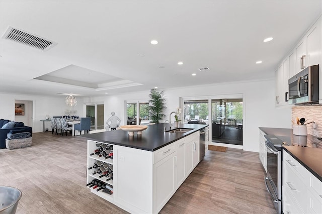 kitchen with a kitchen island with sink, white cabinets, sink, light hardwood / wood-style floors, and stainless steel appliances