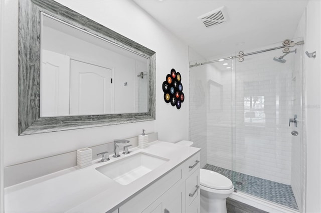 bathroom featuring vanity, toilet, and a shower with door