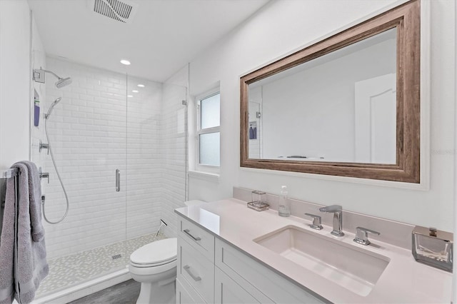 bathroom with hardwood / wood-style floors, vanity, toilet, and a shower with door