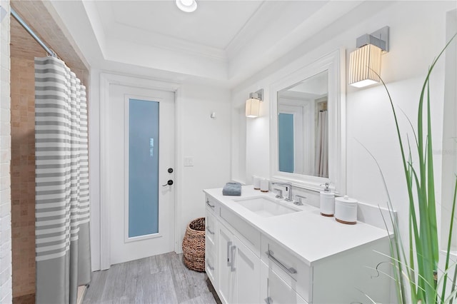 bathroom featuring hardwood / wood-style flooring, vanity, a raised ceiling, and crown molding