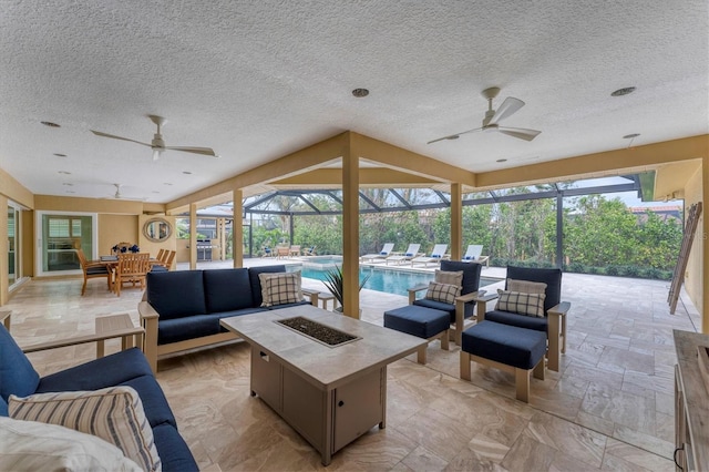 view of patio / terrace with ceiling fan, a lanai, and an outdoor living space with a fire pit