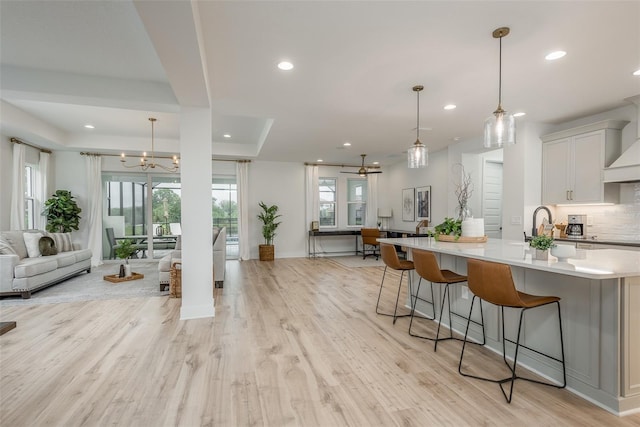 kitchen featuring hanging light fixtures, white cabinets, a breakfast bar area, and light hardwood / wood-style floors