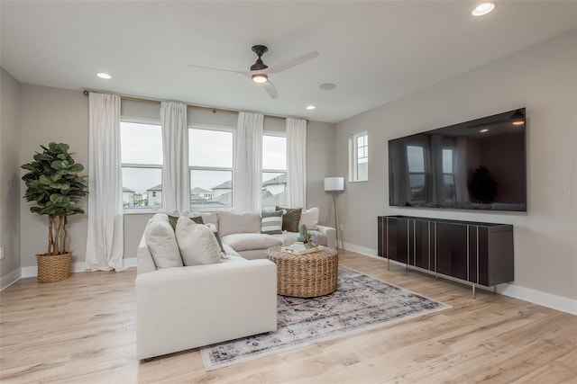 living room featuring ceiling fan, light wood-type flooring, and a healthy amount of sunlight