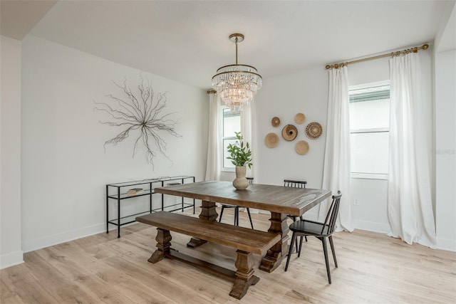 dining room with light hardwood / wood-style floors and a notable chandelier