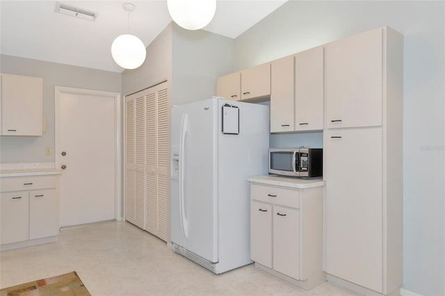 kitchen featuring hanging light fixtures and white refrigerator with ice dispenser