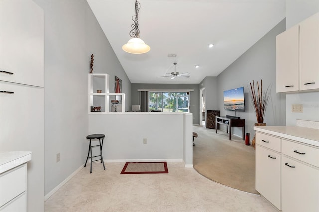 kitchen featuring ceiling fan, light colored carpet, hanging light fixtures, and vaulted ceiling