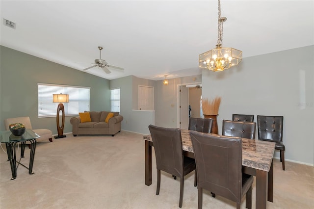 dining room featuring ceiling fan with notable chandelier, light colored carpet, and vaulted ceiling